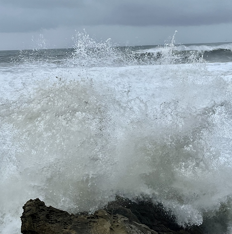 sea with big waves crashing to shore and rocks